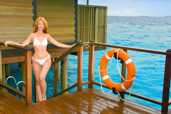 Giovane bella donna si trova in costume da bagno sulla piattaforma a villa sull'acqua, Ma — Foto Stock