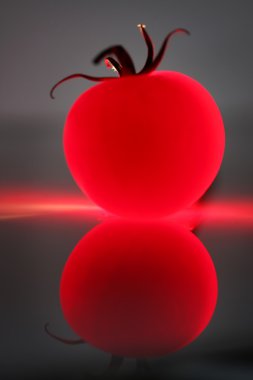 Abstract red tomato against a dark background and its reflection clipart