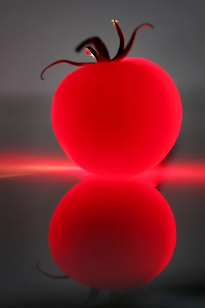 Tomate vermelho abstrato contra um fundo escuro e sua reflexão — Fotografia de Stock