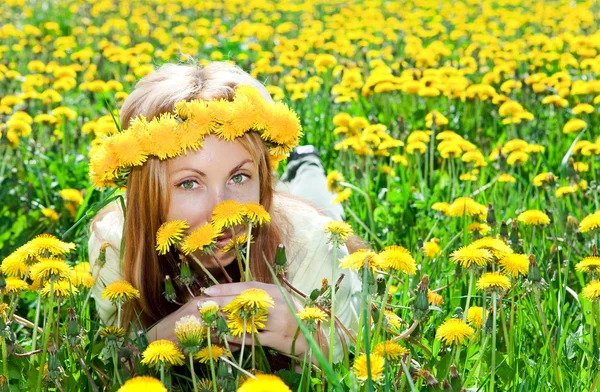 Young pretty woman in wreath of dandelions in the meadow solar day