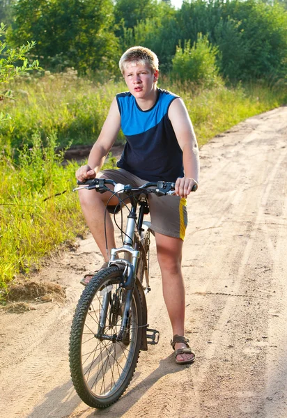 Teenager goes on bicycle on country road — Stock Photo, Image