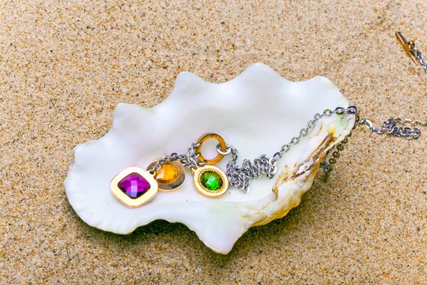 The exotic sea shell with beads lies on sand — Stock Photo, Image