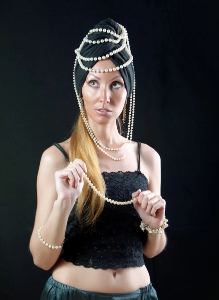 Beautiful young woman in east turban, with pearl beads on dark background — Stock Photo, Image