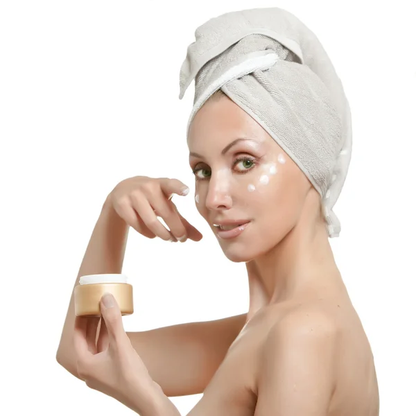 Krásná mladá žena v ručníku s kosmetickým krémem — Stock fotografie
