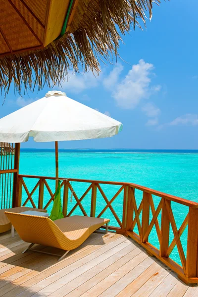 Parasol e chaise salões em um terraço de villa de água, Maldivas . — Fotografia de Stock