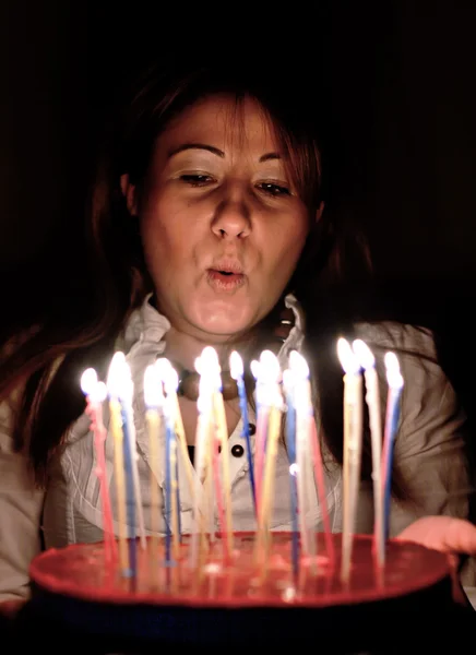 Kvinna blåser ljus på födelsedagstårtan — Stockfoto