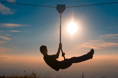 Silhouette of a boy playing with a tyrolean traverse clipart