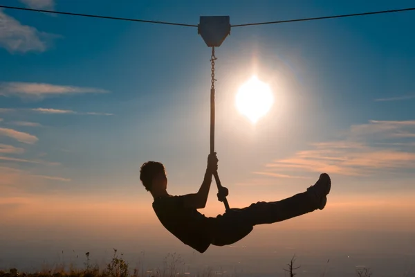 Silhouette of a boy playing with a tyrolean traverse — Stock Photo, Image