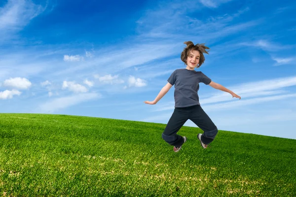 Child jumping on green field — Stock Photo, Image