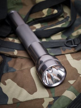 Metallic flashlight on a backpack khaki clipart