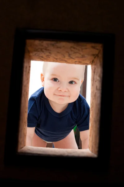 Маленький ребенок смотрит на дыру в стене — стоковое фото