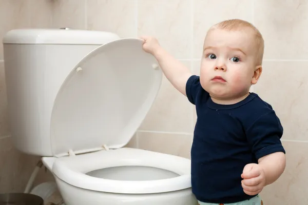 Kleine jongen kijkt in het toilet Stockfoto