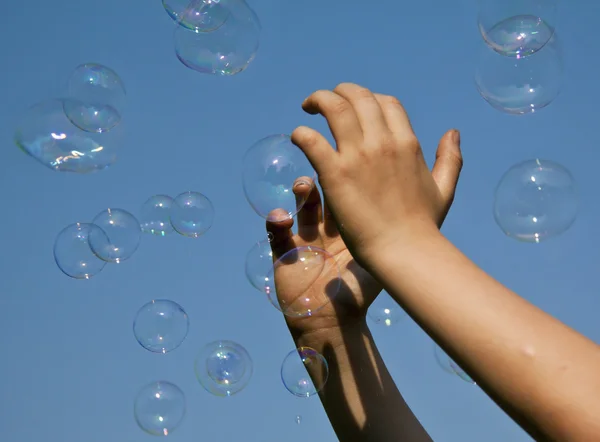 Hands catching bubbles against a blue sky — Stock Photo, Image
