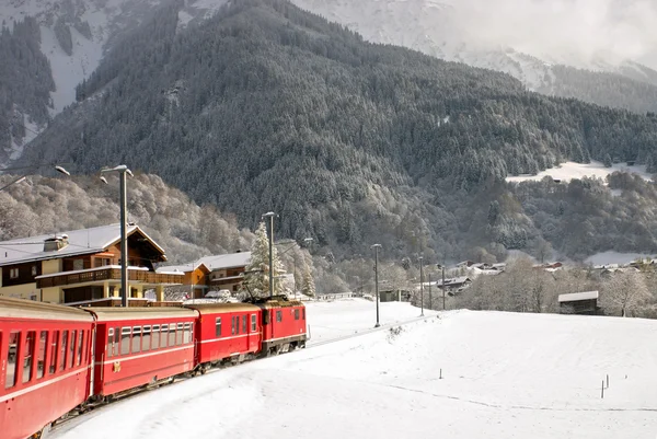 Un train suisse rouge traversant la neige . — Photo