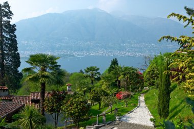 View over Lago Maggiore with beautiful park and houses on the fo clipart