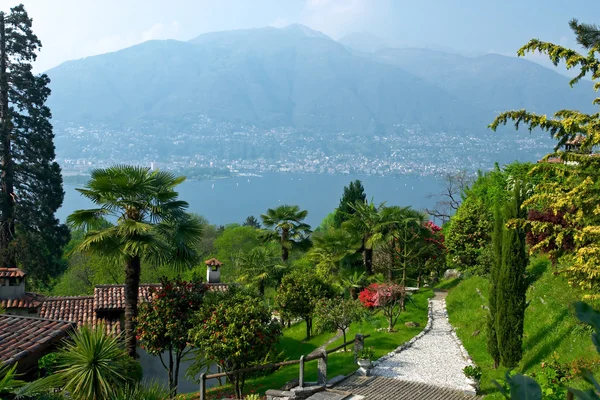 Vista sobre Lago Maggiore com belo parque e casas no fo Imagens De Bancos De Imagens