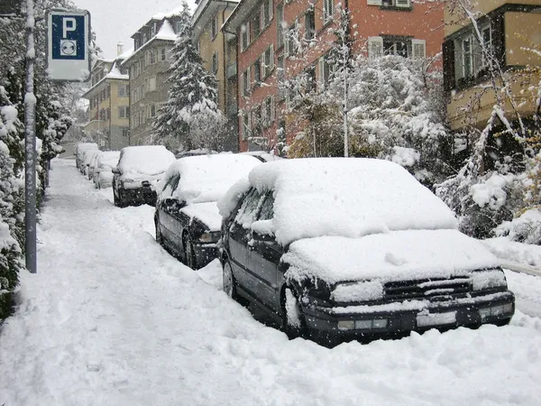 Bilar parkerade på gatan begravd under snö Stockbild