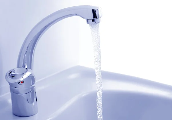 Water flowing from the faucet against the white background — Stock Photo, Image