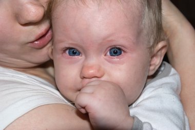 Baby's face with tears, sits on mama's hand clipart