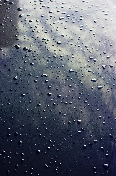 Gotas de agua en la superficie metálica con reflejo del cielo . — Foto de Stock