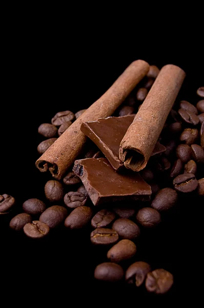 Kaneelstokjes over koffie bonen en chocolade — Stockfoto