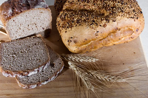 Whole bread and slices with wheat — Stock Photo, Image