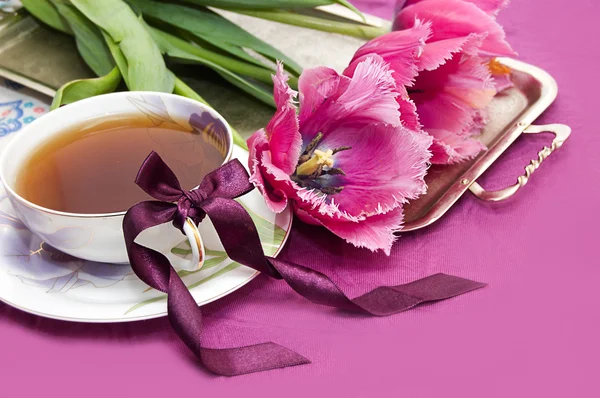 Tulipanes violetas y taza de té — Foto de Stock