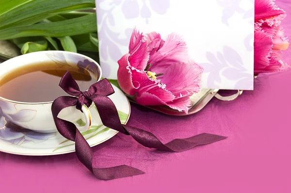 Tea and magenta tulips with blank note