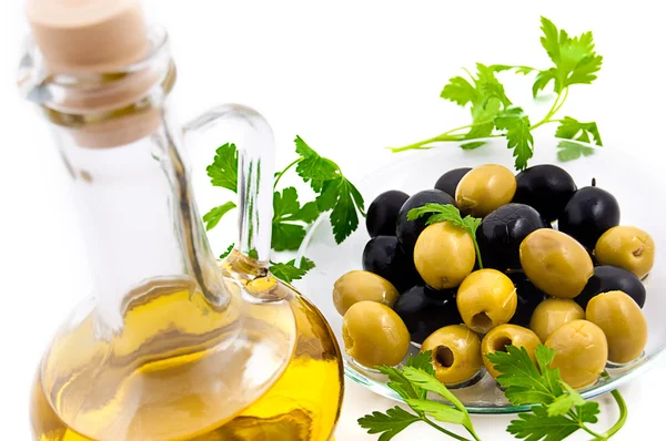 Olives and oil jug with greens — Stock Photo, Image