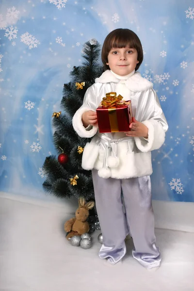 Хлопчик біля ялинки з подарунком в руці — стокове фото