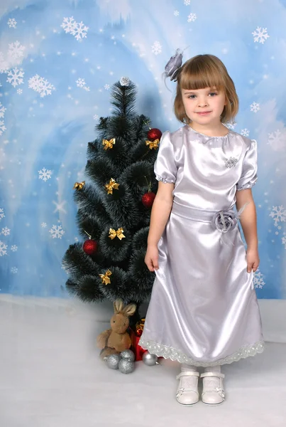 Cute girl in a silver dress around Christmas tree — Stock Photo, Image