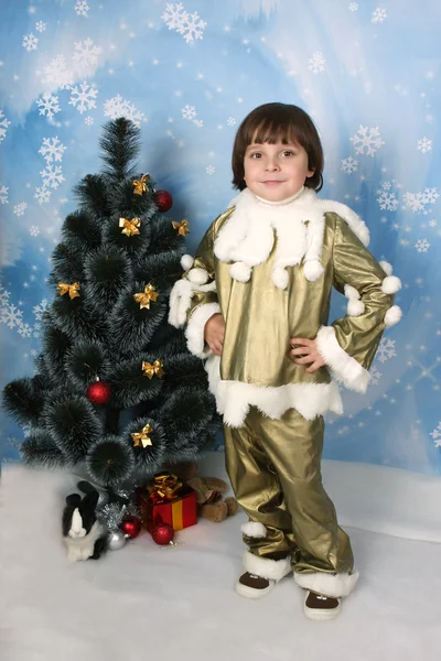 Niño guapo con un disfraz de oro alrededor del árbol de Navidad —  Fotos de Stock