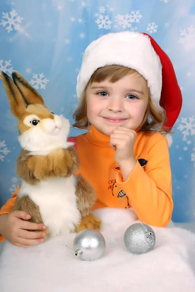 Retrato de una hermosa chica en un sombrero de Santa Claus con un conejo —  Fotos de Stock