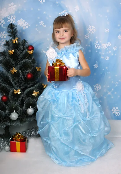 Όμορφο κορίτσι σε ένα σικ μπλε φόρεμα γύρω από ένα χριστουγεννιάτικο δέντρο με — Φωτογραφία Αρχείου