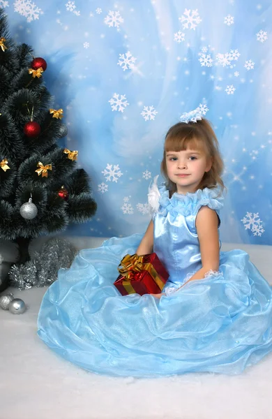 Gyönyörű lány, leült egy elegáns kék ruha, a karácsonyfa körül — Stock Fotó