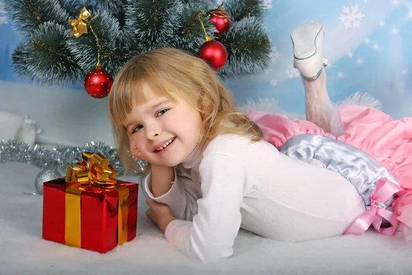 Красивая девушка с подарком лежит рядом с елкой — стоковое фото