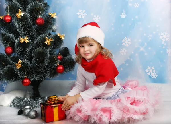 Beautiful girl in the hat of Santa Claus with a gift around the — Stock Photo, Image