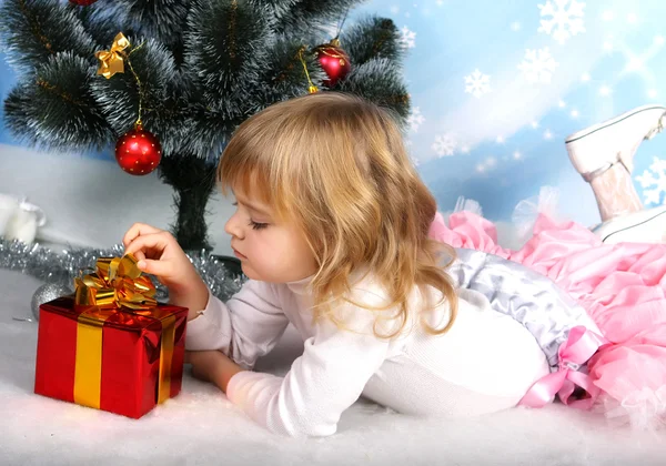 Gyönyörű lány, egy ajándék a karácsonyfa közelében fekszik — Stock Fotó