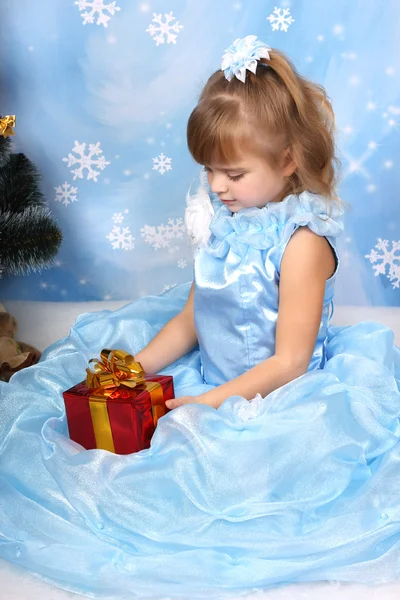 Hermosa chica sentada en un elegante vestido azul alrededor de un árbol de Navidad — Foto de Stock