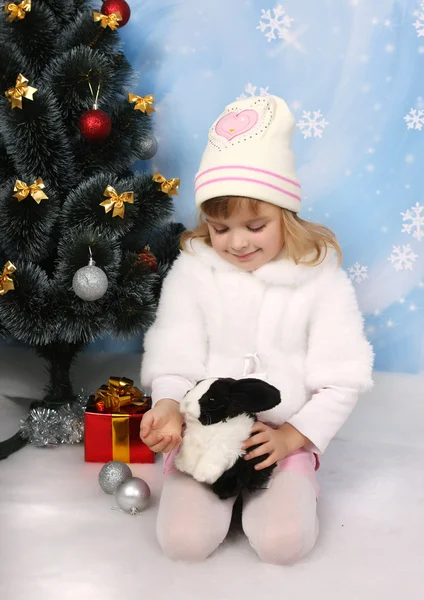 Petite fille en manteau blanc et chapeau avec un lapin autour d'un Chris — Photo