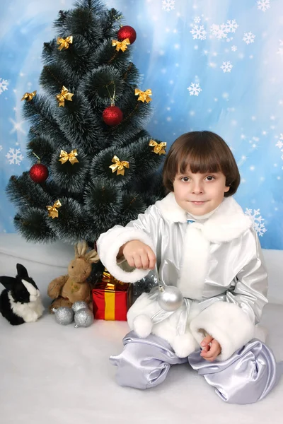 Chico cerca de un árbol de Navidad con bola en la mano — Foto de Stock