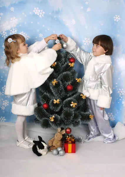 Мальчик и девочка в серебряном платье украшают елку — стоковое фото