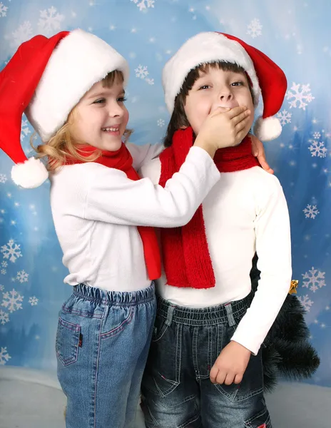 Дівчинка в Санта-Клауса cap, закриває рот palm хлопчиком — стокове фото