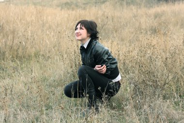 Girl in a field of dry grass looking up at the sky and smiles clipart