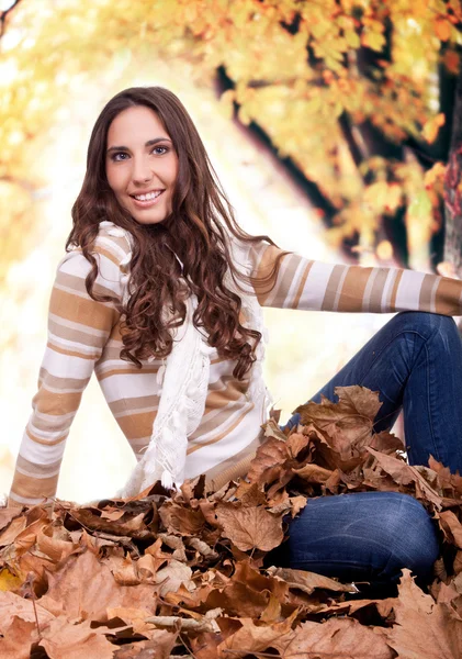 Beautiful autumn woman sitting on leaves outdoor — Stock Photo, Image