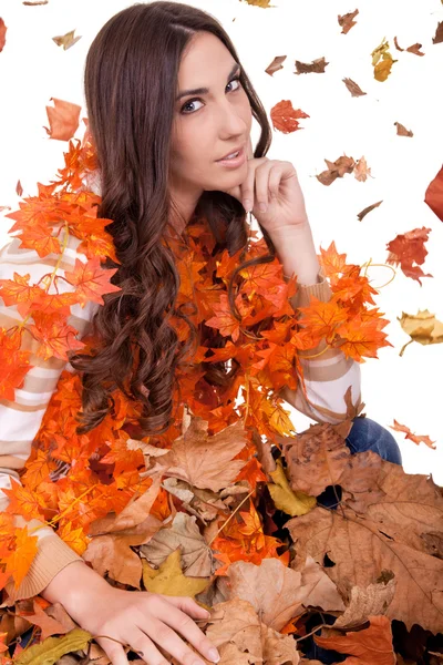 Mulher atraente em uma pilha de folhas de outono — Fotografia de Stock