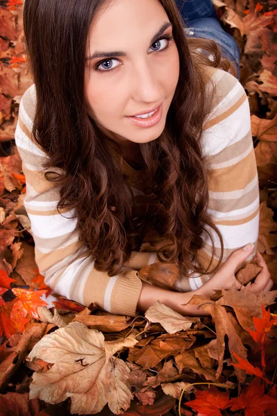 Donna bruna sdraiata sulle foglie autunnali — Foto Stock