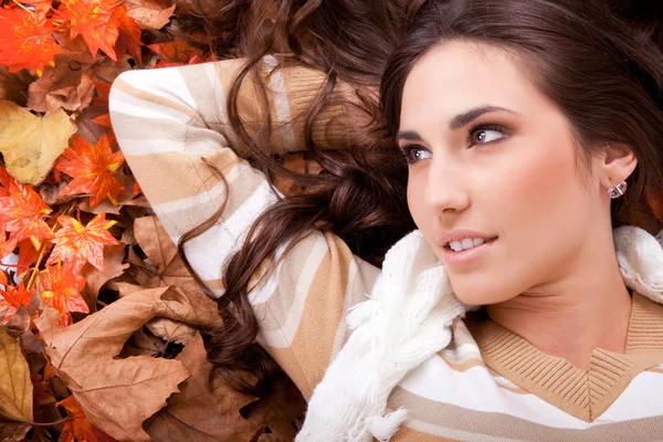 Bruneta žena ležící na podzimní listí — Stock fotografie
