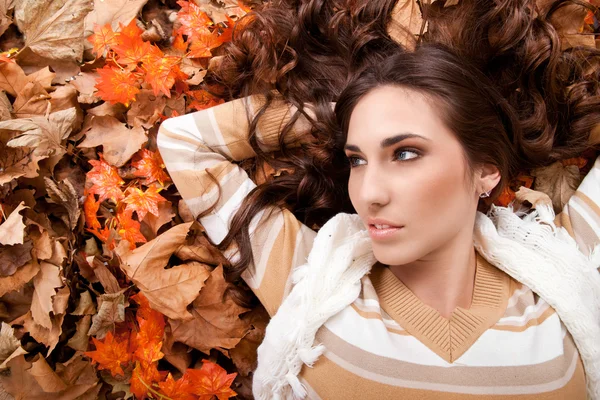 Sonbahar yaprakları üzerinde yatan genç kadın — Stok fotoğraf