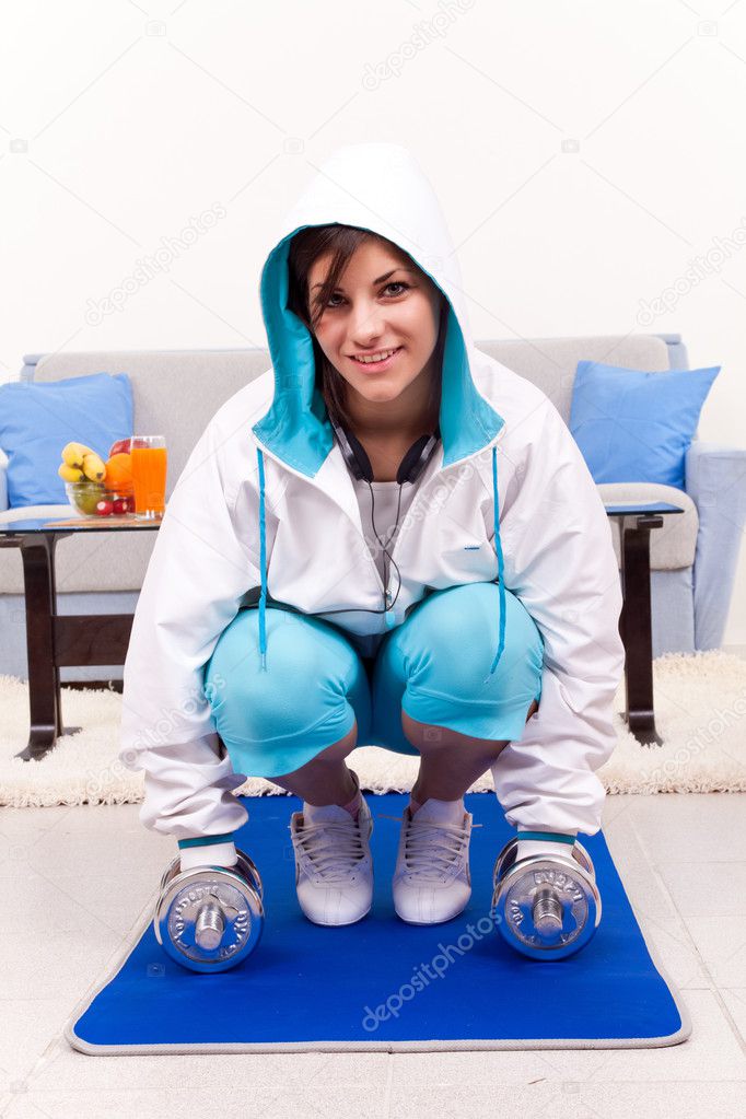 Young woman exercising lifting weights at home
